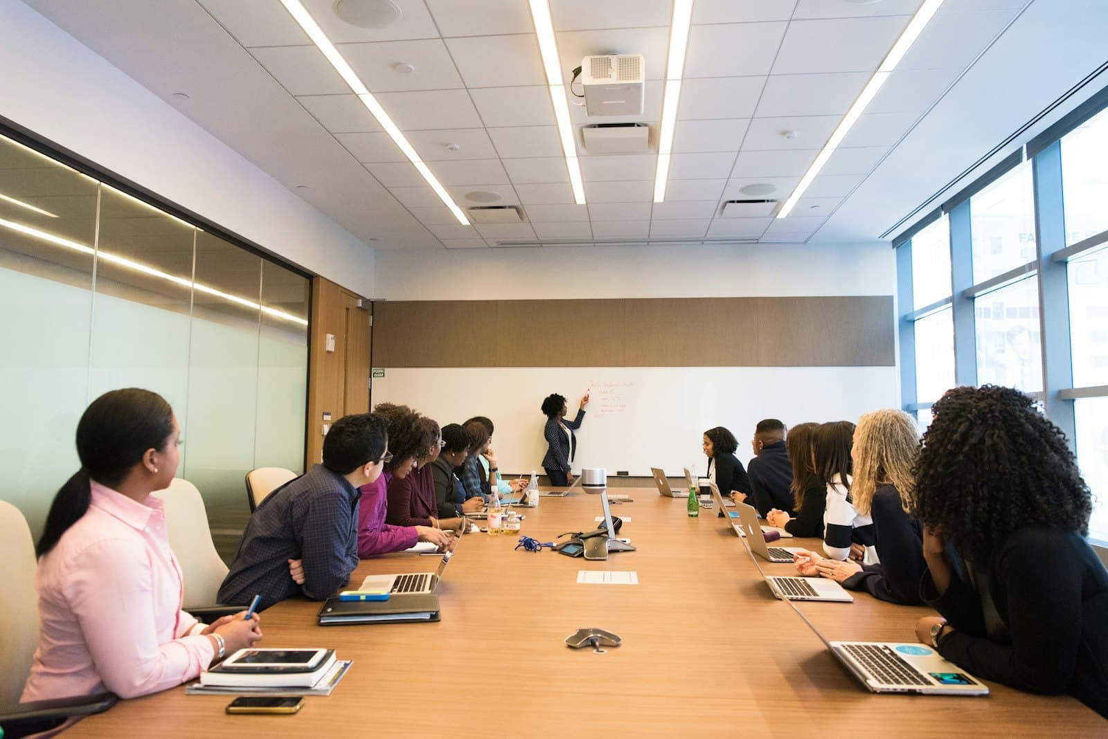A team meeting around a long conference table with laptops open