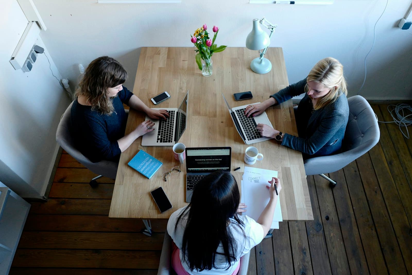 Three colleagues working on laptops around a shared table